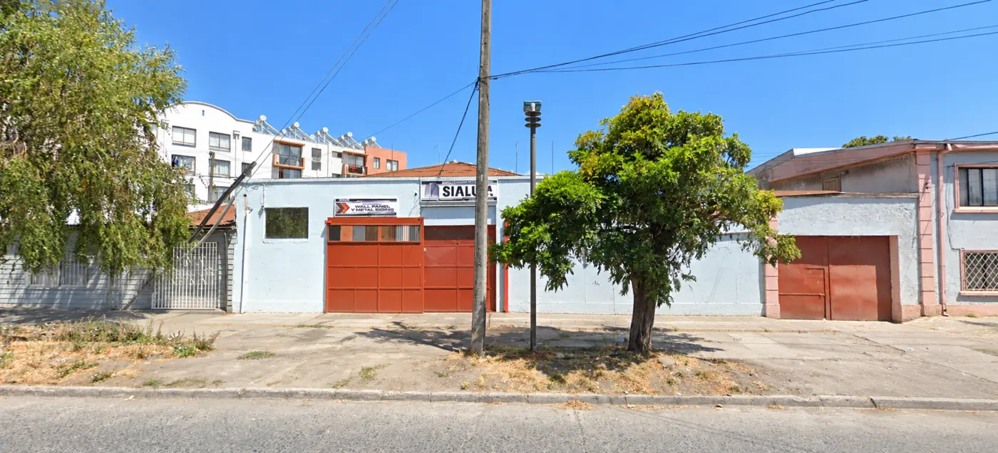 Fachada del local de Sialum, con portones rojizos y letrero de la empresa